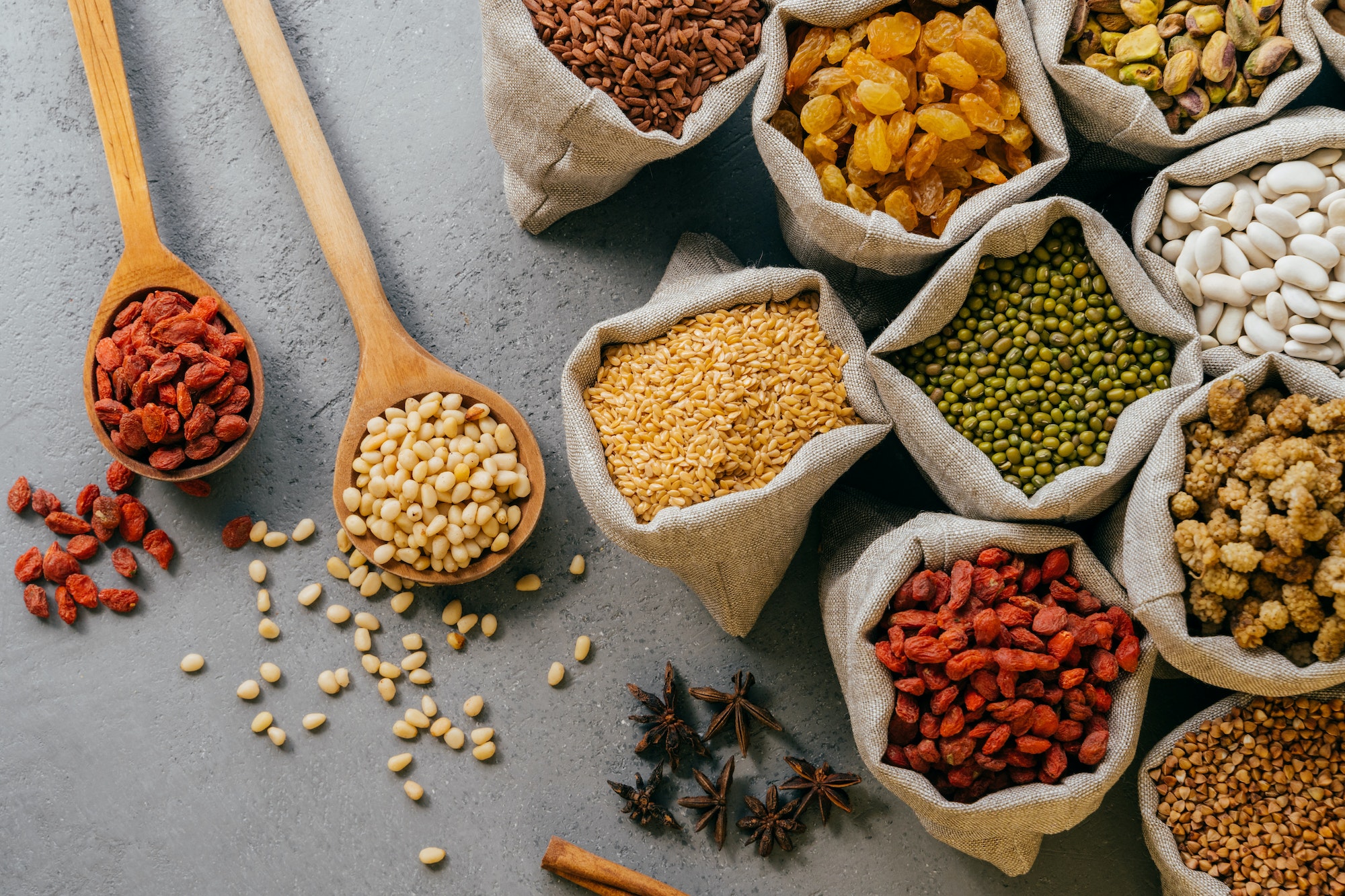 Top view of various beans and colorful dried fruit packed in little burlap sacks
